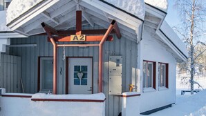 A snow-covered building with a wooden exterior, a white door with a heart-shaped decoration, and a sign labeled "A2". - Hallantytär a2 paritalo by Interhome (Hyrynsalmi)