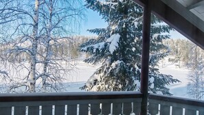 A snowy landscape with a wooden balcony railing and snow-covered trees. - Hallantytär a2 paritalo by Interhome (Hyrynsalmi)