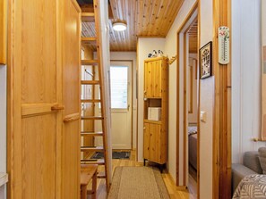 Een houten interieur met een trap, een garderobe, een radiator en een raam.