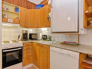 Una cucina compatta con mobili in legno, un frigorifero bianco, un forno a microonde, una macchina da caffè e una lavastoviglie.