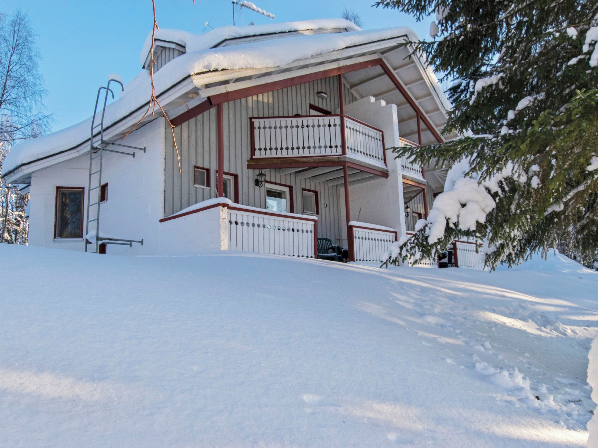 A two-story house with a balcony, surrounded by snow.