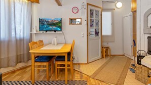 A cozy living room with a wooden dining table, chairs, a flat-screen TV, a fireplace, and a small stool. - Hallantytär a2 paritalo by Interhome (Hyrynsalmi)