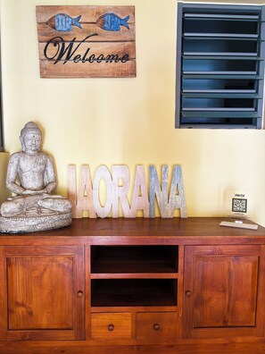 Un mobile in legno con una statua di Buddha, un cartello di benvenuto e un cartello con un codice QR.