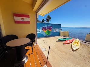 Una veranda con tavolo e sedie, un murale e kayak sulla spiaggia.