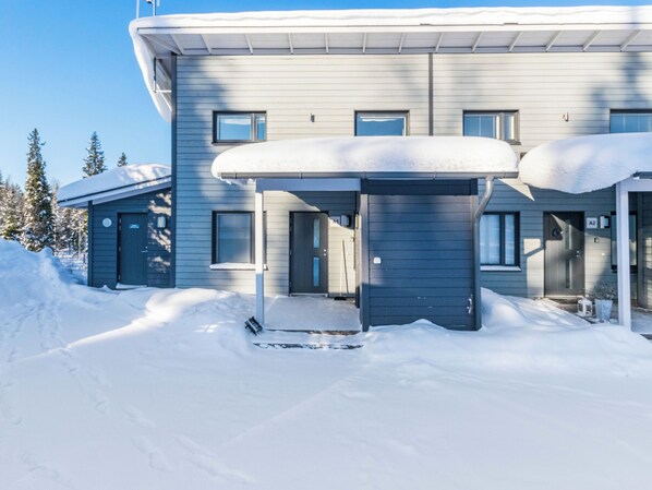 Un bâtiment moderne doté d’une entrée abritée et d’un toit recouvert de neige.