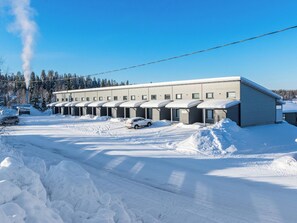 A building with multiple rooms, a parking area, and a snow-covered landscape.