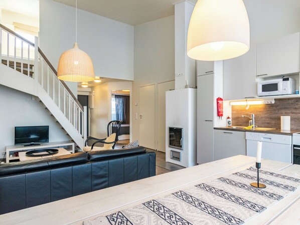 A modern kitchen with a microwave, stove, and sink. There is a dining area with a table and chairs.