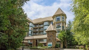 A multi-story hotel with a stone tower entrance, balconies, and a covered walkway.