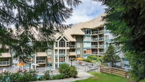 A multi-story hotel with balconies, a swimming pool, and a well-maintained garden.