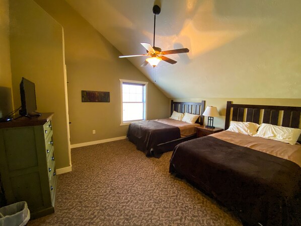 A bedroom with two beds, a ceiling fan, a window, and a dresser.