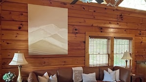 A cozy log cabin interior with a sectional sofa, a wooden coffee table, and a ceiling fan. - LITTLE CUBBIE Location! Views! Pool!! (Sevierville)