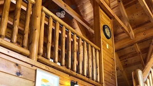 A wooden staircase with a railing, a clock, and framed artwork on the walls. - LITTLE CUBBIE Location! Views! Pool!! (Sevierville)