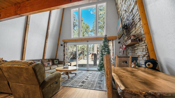 A cozy living room with a wooden table, a sofa, and a fireplace. - Sherwood Pines - Pool Table, Fireplace, Fenced Yard (Big Bear City)