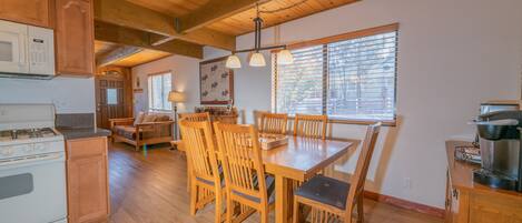 A wooden kitchen with a dining table and chairs, a stove, and a microwave.
