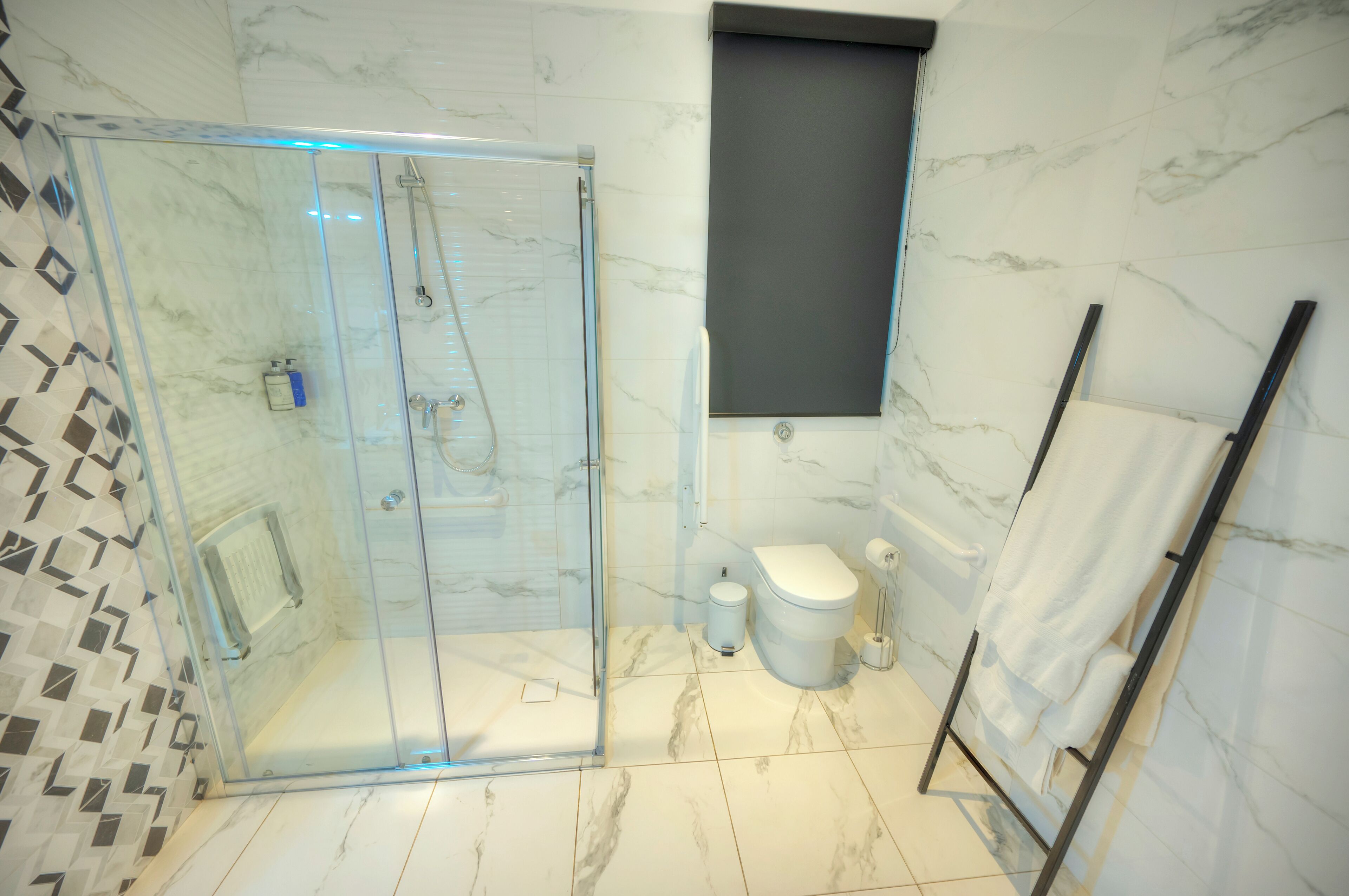 Et moderne badeværelse med bruseniche, toilet og håndklædetørrestativ.