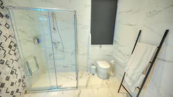 Et moderne badeværelse med bruseniche, toilet og håndklædetørrestativ.