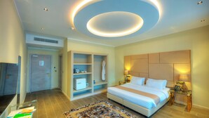 Een moderne hotelkamer met een groot bed, een inbouwkleerkast en een ronde plafondlamp.