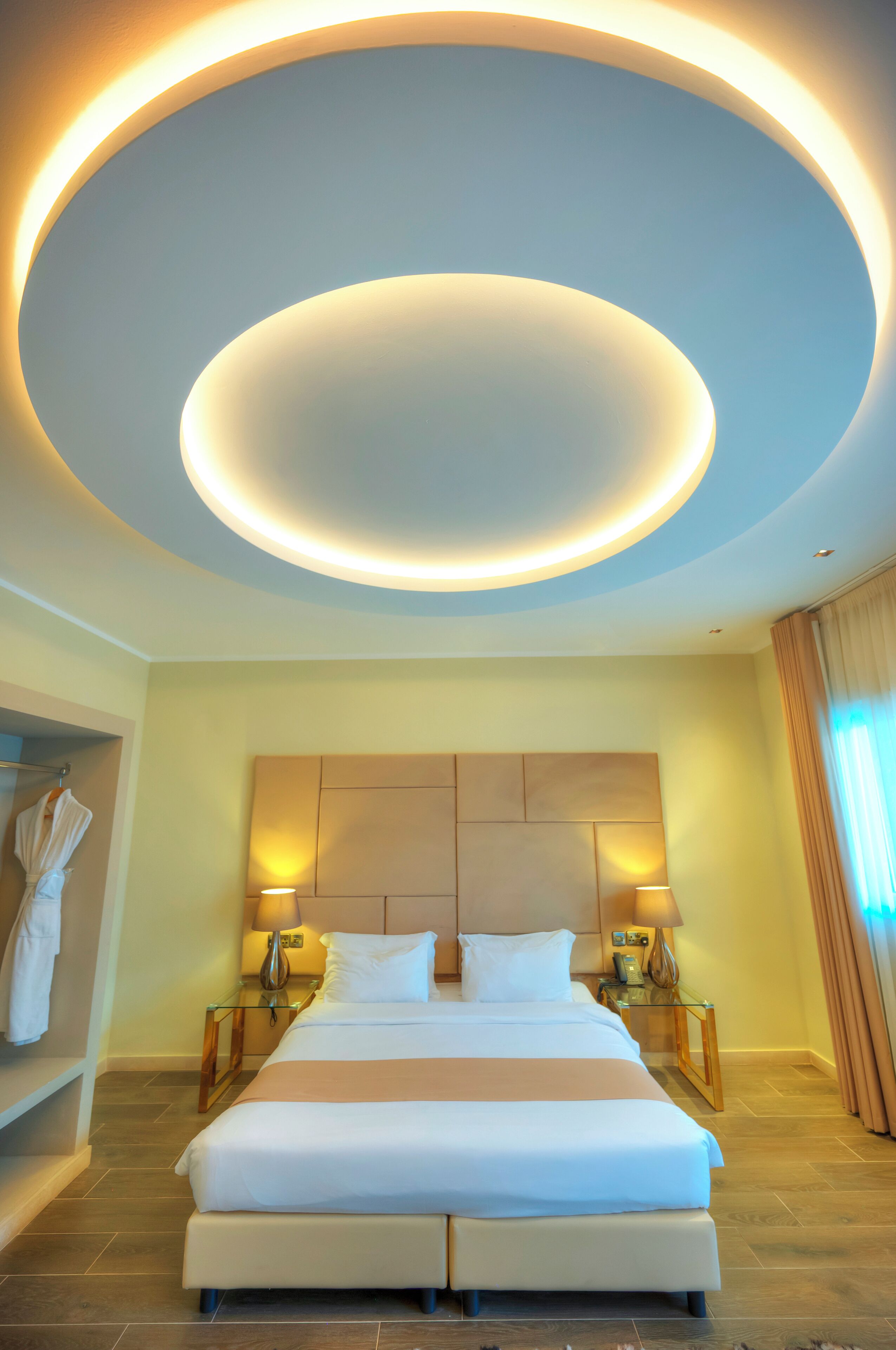 A modern hotel room with a large bed, bedside lamps, and a circular ceiling light fixture.