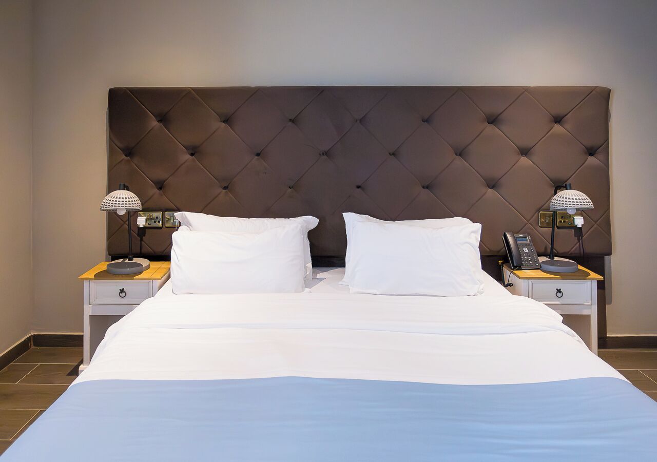 A hotel room with a large bed, two bedside tables, and a tufted headboard.
