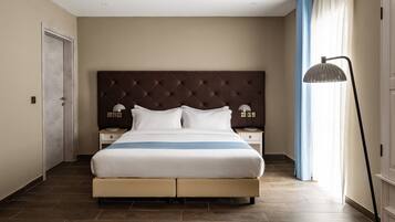A hotel room with a large bed, two bedside tables, a headboard, and a floor lamp.