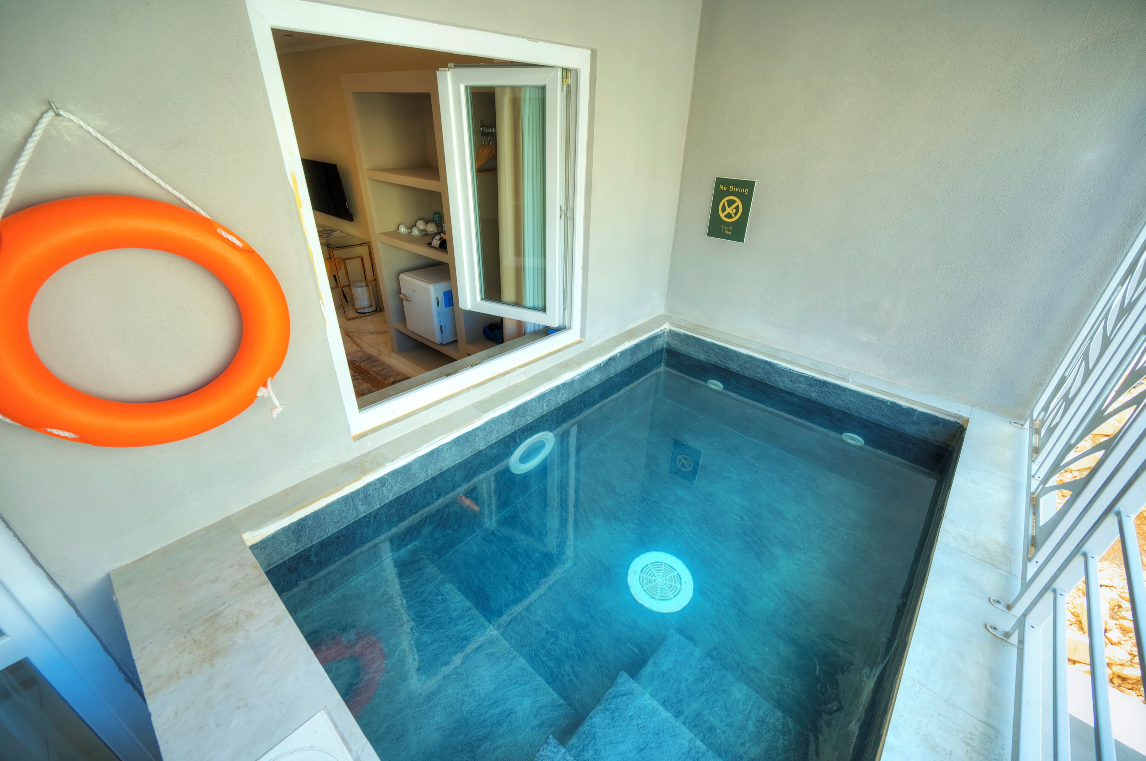 A swimming pool with a glass wall, a window, and a 'No Diving' sign.