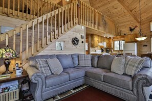 A wooden interior with a sofa, a staircase, and a kitchen area.