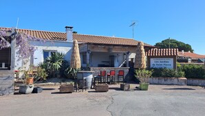 A residential property named Parc Residential de Loisirs de Saint Pierre. It features a tiled roof, a small outdoor seating area with wooden tables and chairs, and potted plants. - Chalet in a private park in Saint Pierre D'oléron (Saint-Pierre-d'Oléron)