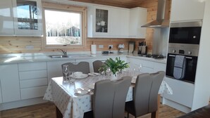 Una cocina moderna con armarios blancos, una mesa de comedor para cuatro comensales y un horno empotrado.