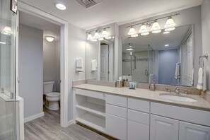 A modern bathroom with a large mirror, a shower, and a toilet.