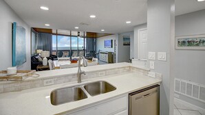 A modern kitchen with a double sink, white countertops, and a built-in dishwasher.