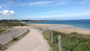 A coastal road leading to a beach with a clear sky. - Longère Bretonne Dans un Écrin de Verdure (Pléboulle)