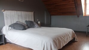 A bedroom with a wooden ceiling, a bed with white bedding, and a herringbone-patterned floor. - Longère Bretonne Dans un Écrin de Verdure (Pléboulle)