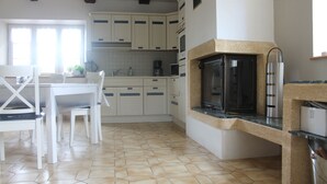A kitchen with white cabinets, a black oven, and a tiled floor. - Longère Bretonne Dans un Écrin de Verdure (Pléboulle)