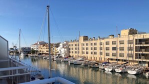 Puerto deportivo con barcos amarrados, edificios a lo largo de la costa y cielo despejado.