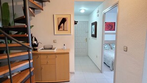 Un interior moderno con una escalera espiral, un mueble de madera y un pasillo que conduce a un dormitorio.
