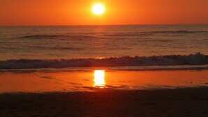 Una puesta de sol sobre el océano con olas que se acercan a la orilla.