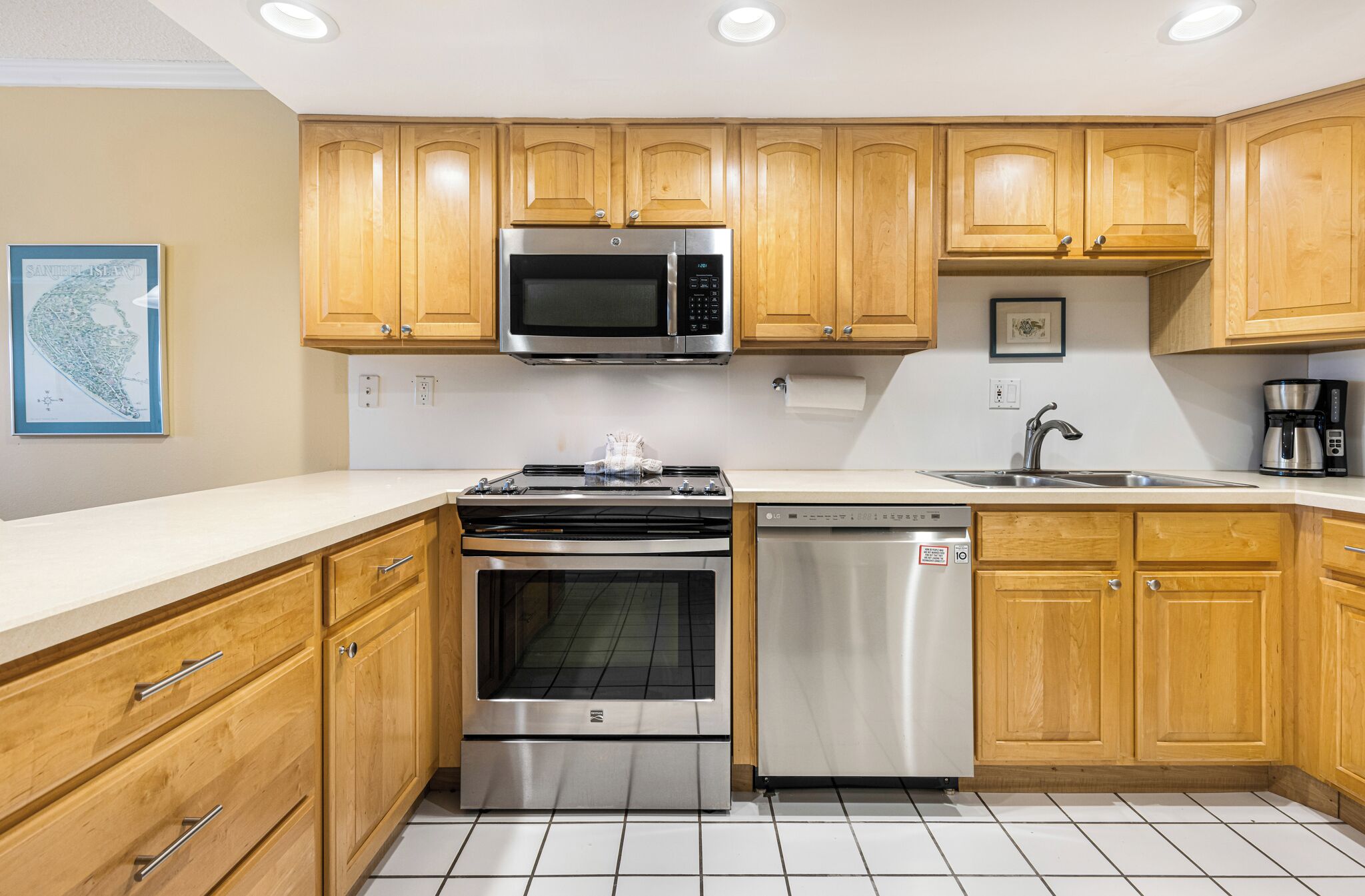 A modern kitchen with wooden cabinets, stainless steel appliances including a microwave, oven, and dishwasher, and a white countertop.