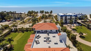 Eine Luftaufnahme eines Hotels mit rotem Ziegeldach, Poolanlage und Strandlage.