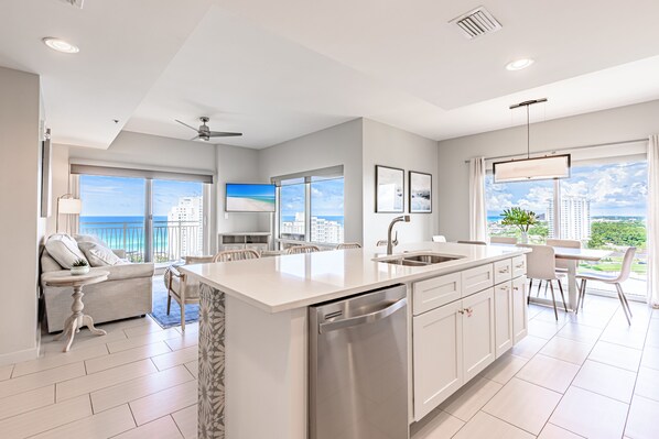A modern kitchen with a large island, white cabinetry, and a view of the ocean.