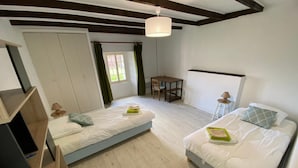 Quarto com duas camas, uma escrivaninha de madeira, uma cadeira, uma mesa e um lustre.