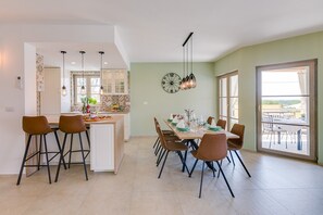 Una cucina moderna con isola centrale, sgabelli da bar e zona pranzo con tavolo apparecchiato per sei.