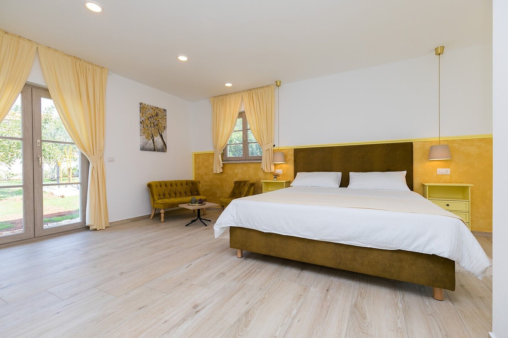 Un dormitorio con una cama grande, un sofá, una silla y una mesita.