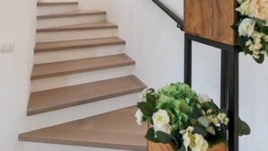 Eine Treppe mit Holzboden, einem schwarzen Geländer und einem Holz-Pflanzkasten mit Blumen.