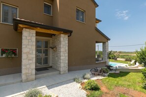 Una casa a due piani con facciata in pietra, un portico e una piscina.