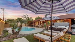 Un jardin avec une piscine, des chaises longues et un jacuzzi.