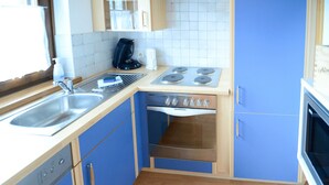 A compact kitchen with a sink, stove, and oven. - Ferienwohnung 50 m² (Kötschach-Mauthen)