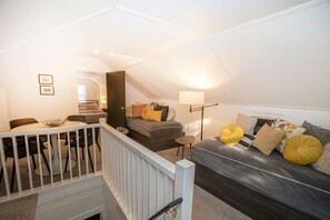 Une chambre de style loft moderne, comprenant un coin repas, un escalier et une grande fenêtre.