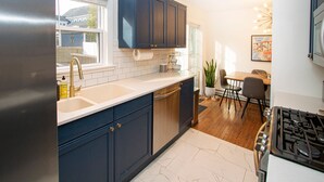 Une cuisine moderne avec des meubles de couleur bleu foncé, un réfrigérateur en acier inoxydable et une cuisinière à gaz.