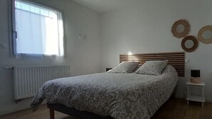 Une chambre à coucher avec un lit, une table de chevet, un radiateur et une fenêtre.