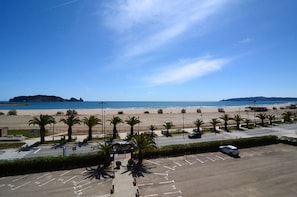Un estacionamiento con palmeras, playa y cielo despejado.